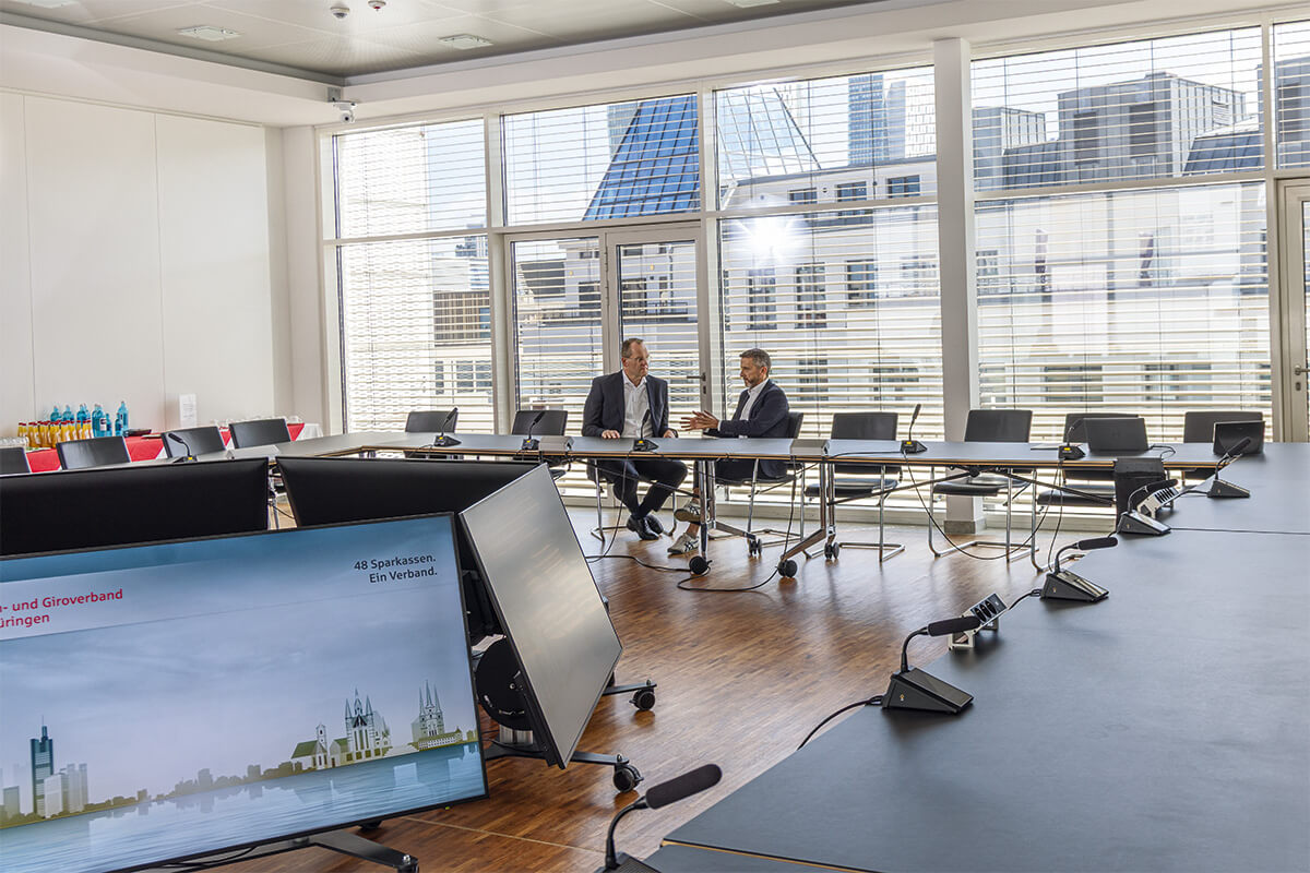 zwei Männer unterhalten sich in einem großen Konferenzraum