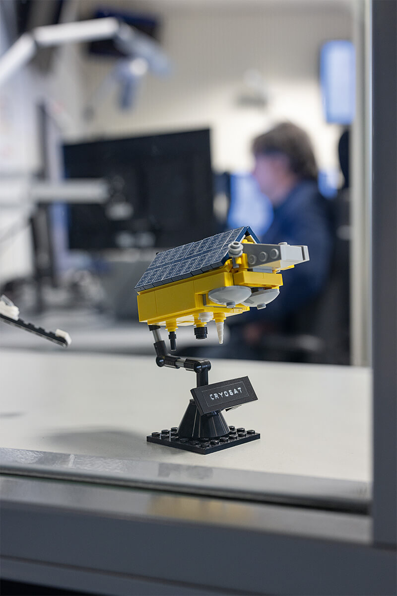 Lego-Modell des ESA-Satelliten CryoSat mit Solarpaneelen auf einem schwarzen Ständer mit Namensschild „CRYOSAT“