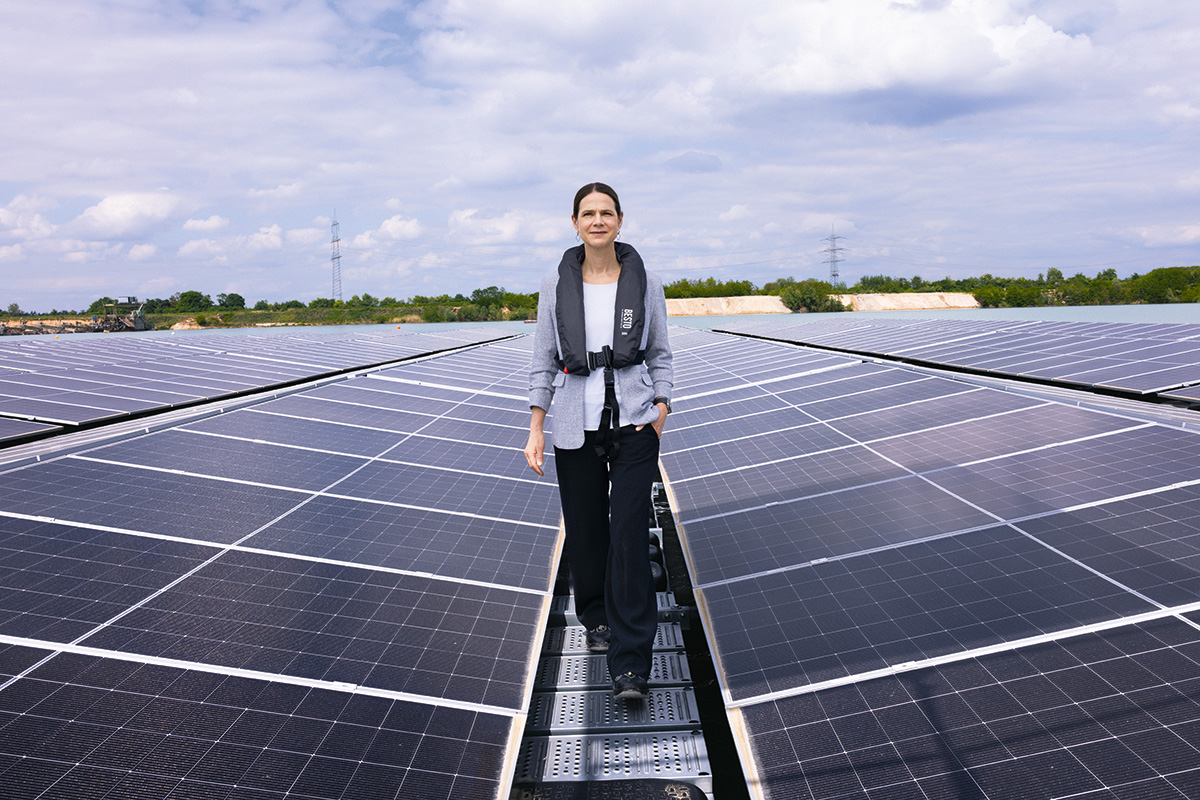 Julia Klinger auf einem Wartungssteg zwischen Solarmodulen in einem großen Solarpark.