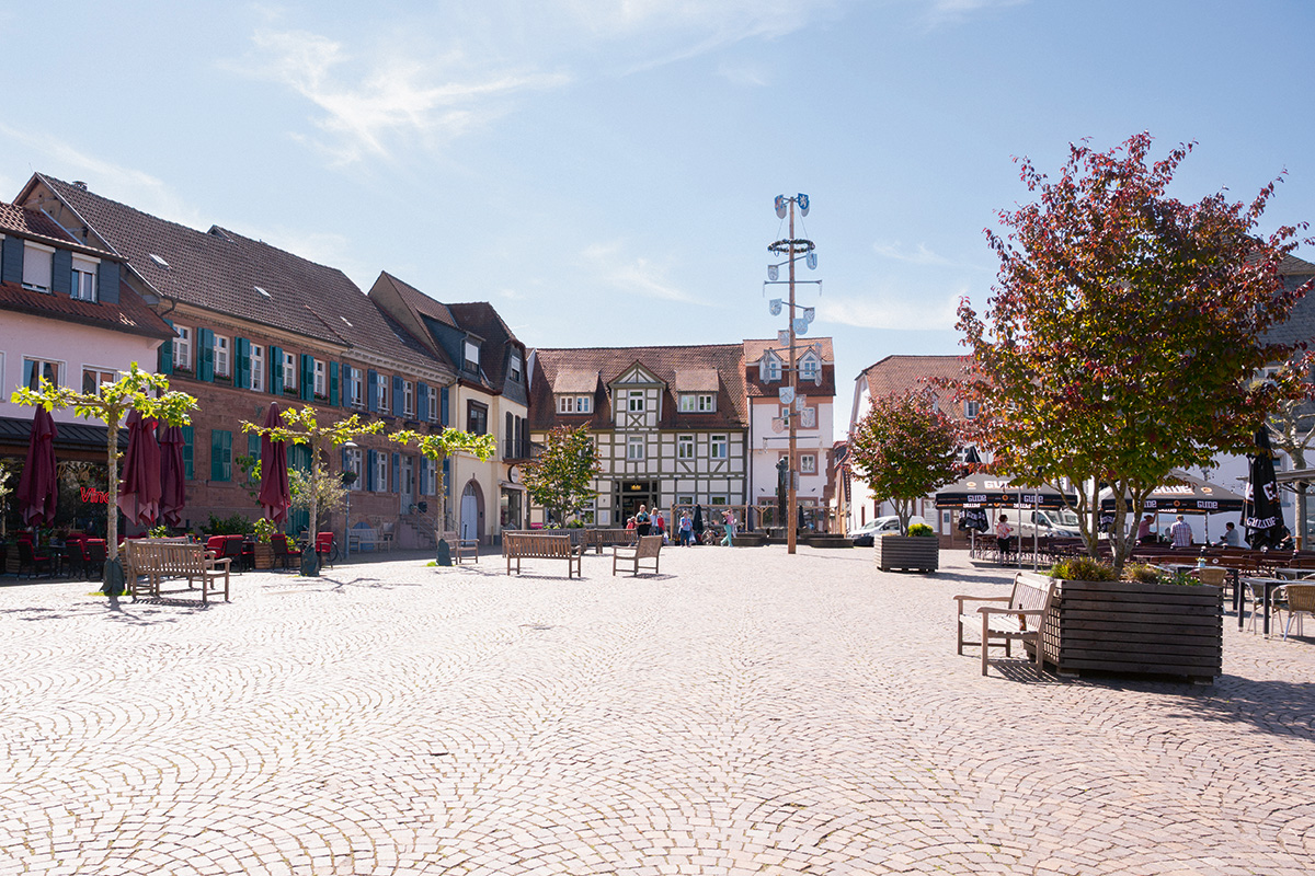 Historischer Stadtplatz mit Fachwerkhäusern und Außengastronomie.