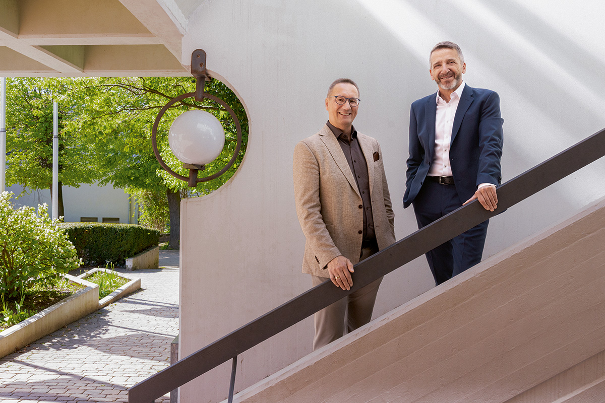 Sascha Ahnert und Albrecht Förster stehen auf einer Treppe und lächeln in die Kamera.
