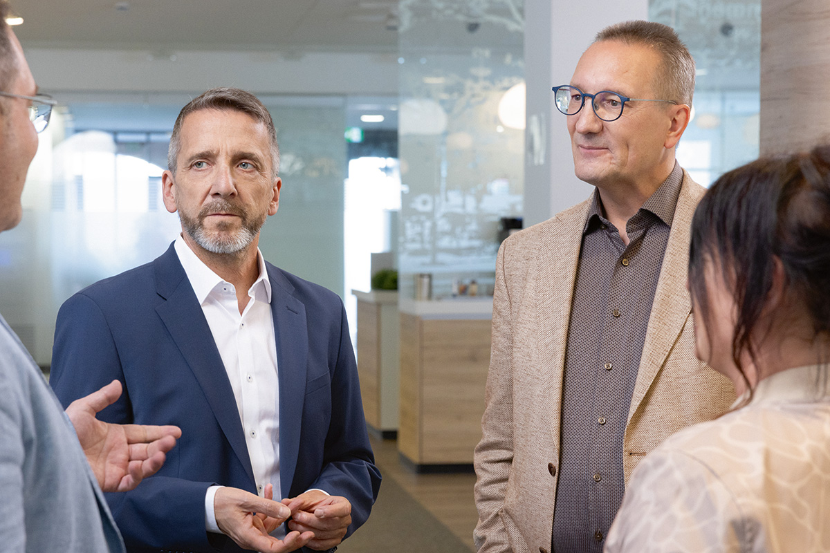 Vier Personen im Gespräch in einem modernen Büro.